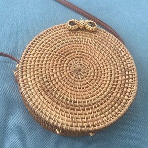 Round wicker crossbody in natural tan color with dark brown strap